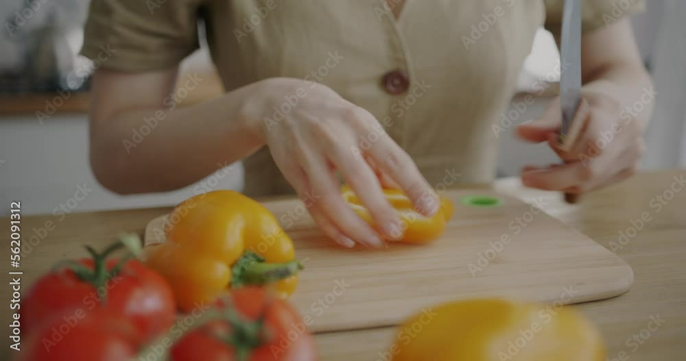 Close-up of female hand cutting fresh pepper cooking salad making healthy meal at kitchen table. Nutrition and vegetarian diet concept. Close-up of female hand cutting fresh pepper cooking salad making healthy meal at kitchen table. Nutrition and vegetarian diet concept.