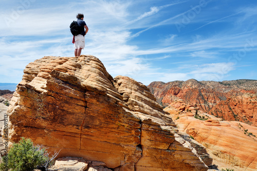 Young male hiker admiring the scenic view of marvelous red and white sandstone formations of Yant Flat in Utah, USA.