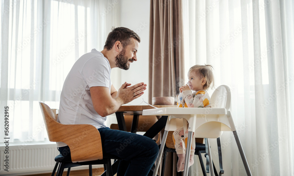 A girl with allergies is sitting in her chair and inhaling herself while father clapping. A girl with allergies is sitting in her chair and inhaling herself while father clapping.