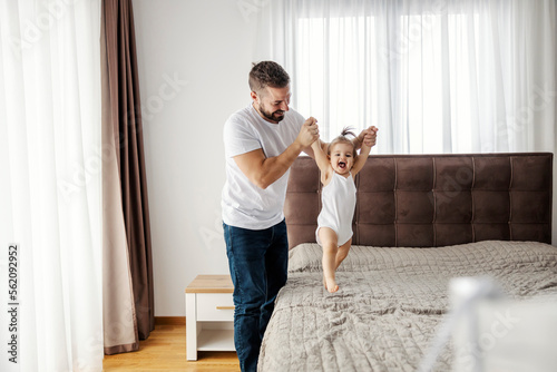Принти на полотні A happy father is teaching his baby girl how to walk.