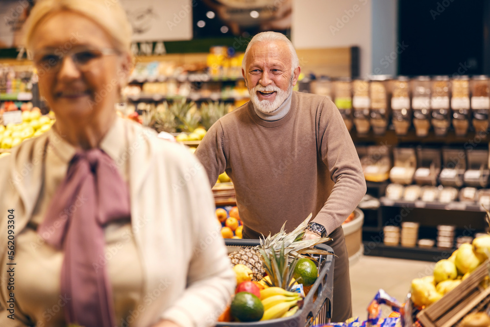 Senior man is pushing shopping cart full of groceries while shopping in hypermarket. Senior man is pushing shopping cart full of groceries while shopping in hypermarket.