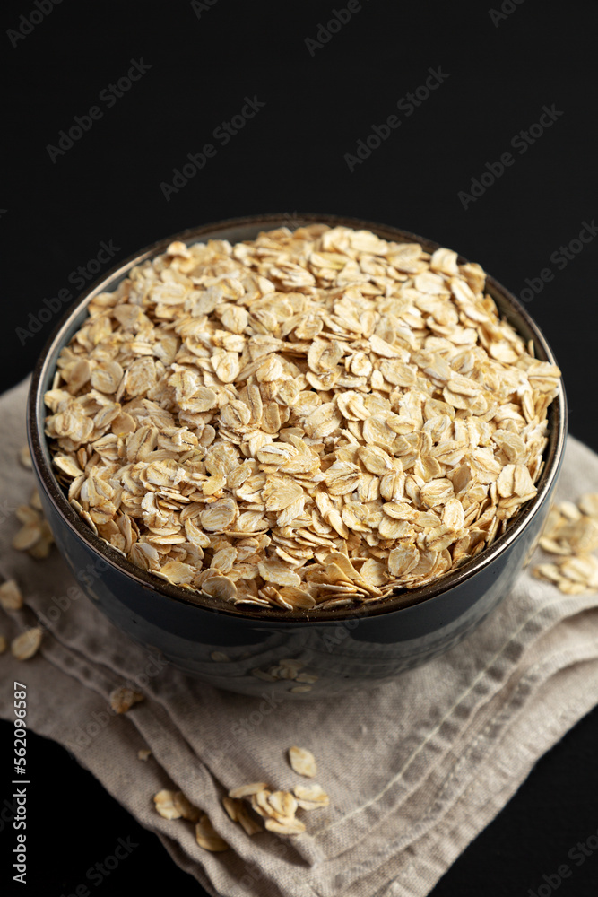 Wholegrain Oat Flakes in a Bowl on a black background, side view. Wholegrain Oat Flakes in a Bowl on a black background, side view.
