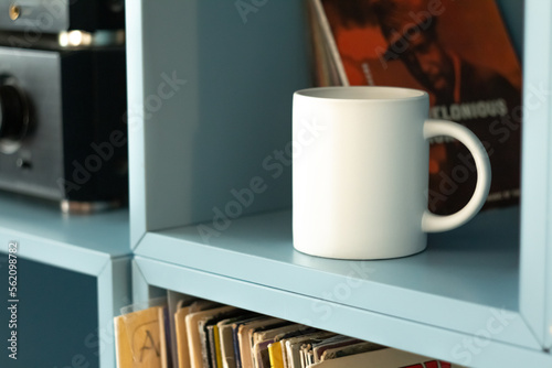 White mug on shelf with vinyls.