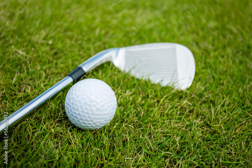 Golf clubs and ball on a green grass, background