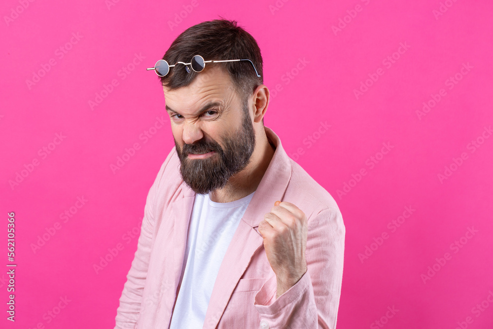 Obraz premium Bearded man dressed in a pink jacket with glasses. Emotional studio portrait.