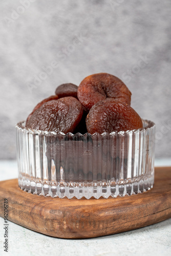 Dried apricots on stone background. Dark dried apricots in a glass bowl. Diet foods. close up photo