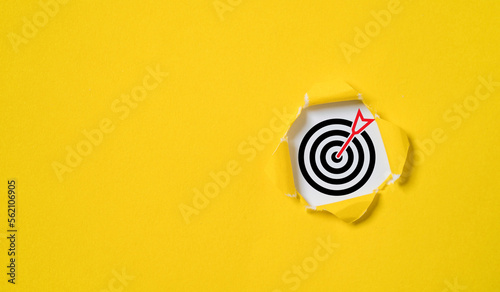 Dartboard with arrow inside of yellow punched paper for setup business objective target and goal concept.