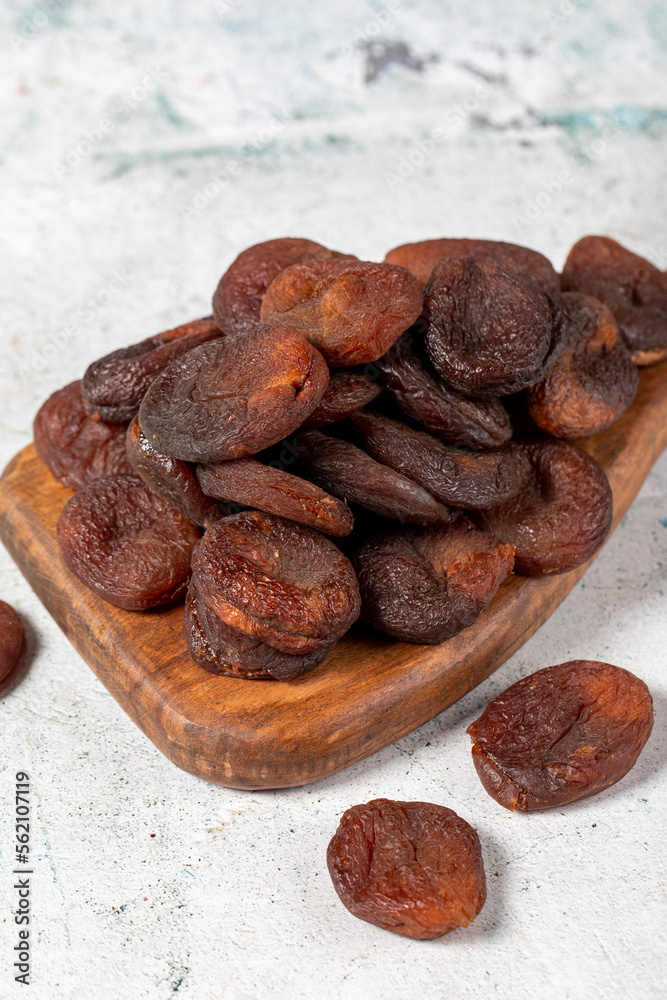 Obraz premium Dried apricots on stone background. Dark dried apricots on a wooden serving board. Diet foods. close up