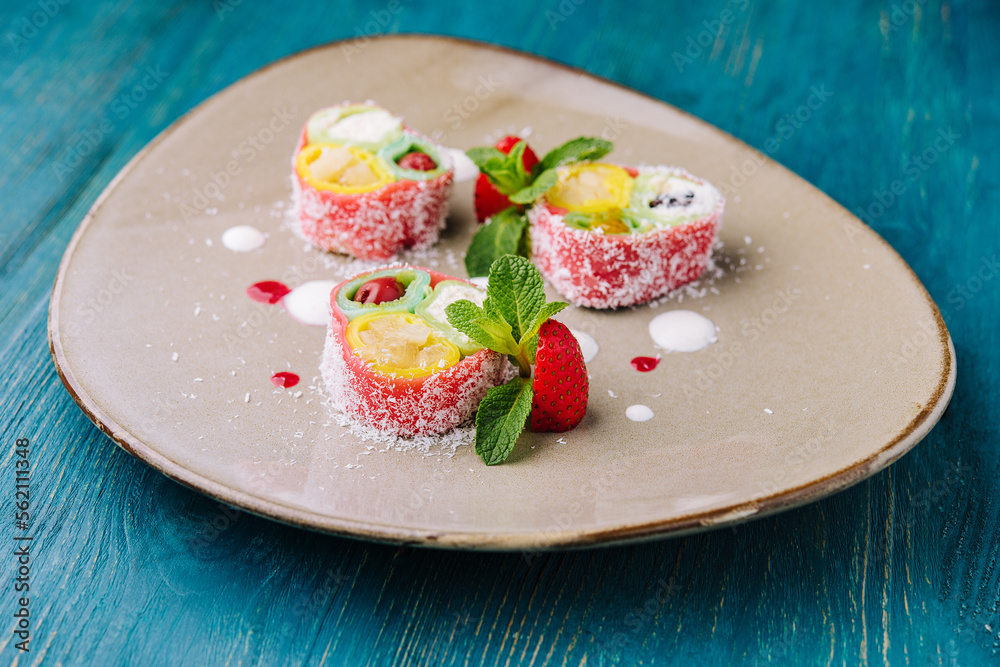 rolls of pink pancakes with different fruits and berries