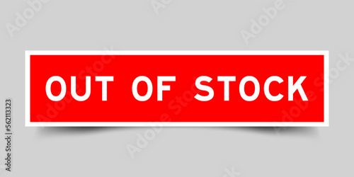 Red color square label sticker with word out of stock on gray background