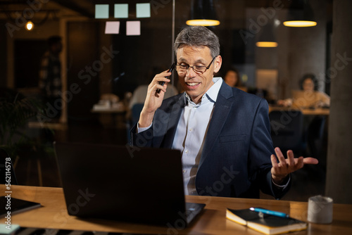 Businessman in office. Handsome man talking on phone at work