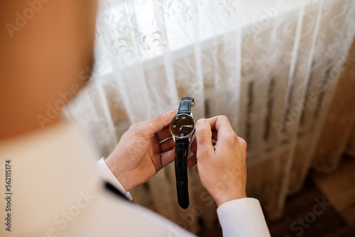Businessman checking time on his wrist watch, man putting clock on hand. Groom getting ready in the morning before wedding ceremony. Men Fashion