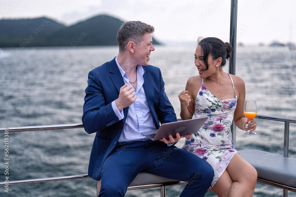 Business man and girl friend on holiday sailing on the yacht check laptop and get good news