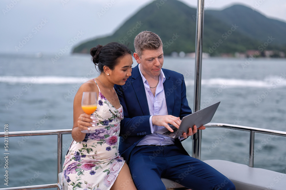 Business man and girl friend on holiday sailing on the yacht check laptop and get good news Business man and girl friend on holiday sailing on the yacht check laptop and get good news