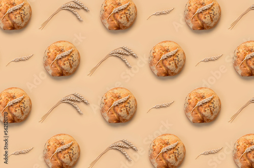 Creative layout with bread. Bread background pattern. Fresh tasty bread, ears of wheat on beige background flat lay top view. Bakery, healthy food concept. Wheat bread, round classic.