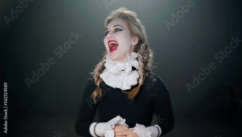 Medium shot portrait of young Caucasian actress in costume imitating insanity laughing out loud looking at camera. Talented female performer posing on stage in theater playing madness role