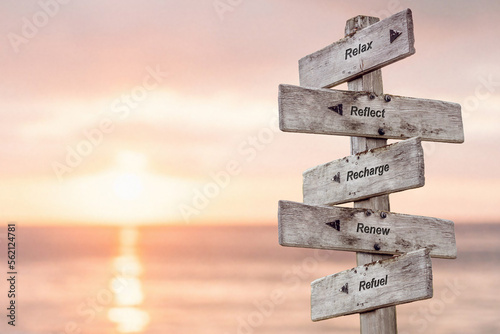 relax reflect recharge renew refuel five word quote on wooden signpost outdoors with sunset background.