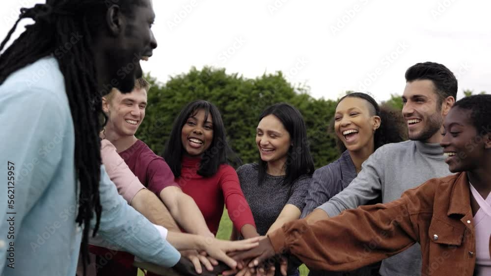 Happy young group of people stacking hands outdoor
