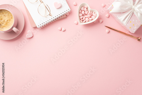 Valentine's Day concept. Top view photo of notebook stylish glasses pen heart shaped saucer with sprinkles present box and cup of coffee on isolated pastel pink background with empty space