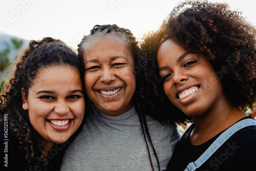 Portrait of happy African mother and daughters having fun outdoor looking at camera - Love family concept - Focus on right girl