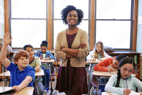 Portrait, student question and black woman teacher in classroom or middle school. Education, arms crossed or boy raising hand to answer questions, studying or learning help with happy female educator