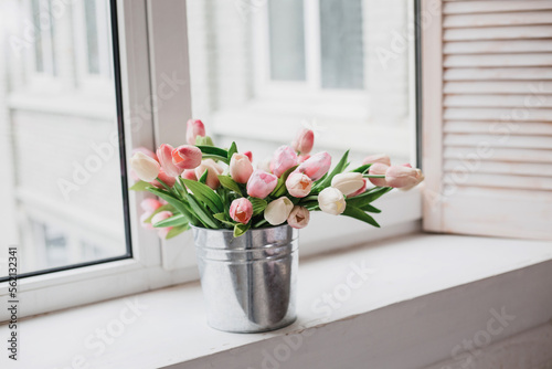  Spring flowers in vase on breakfast tray. White tulips in a vase in a rustic interior. Cozy apartment in boho chic style interior