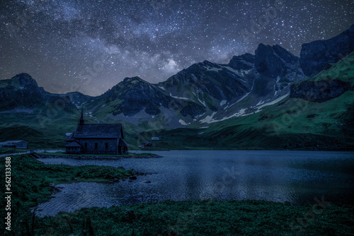 Magical Night in the Swiss Alps: Small Chapel by the Mountain Lake with Milky Way and Moonlight