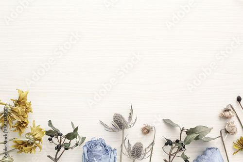 Pretty decorative frame with whitish wood grain background and dried flowers, including blue roses and yellow flowers