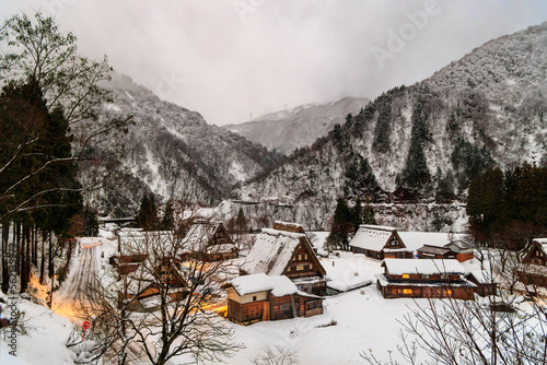 Lights on in snowy UNESCO World Heritage village in mountain landscape at dawn