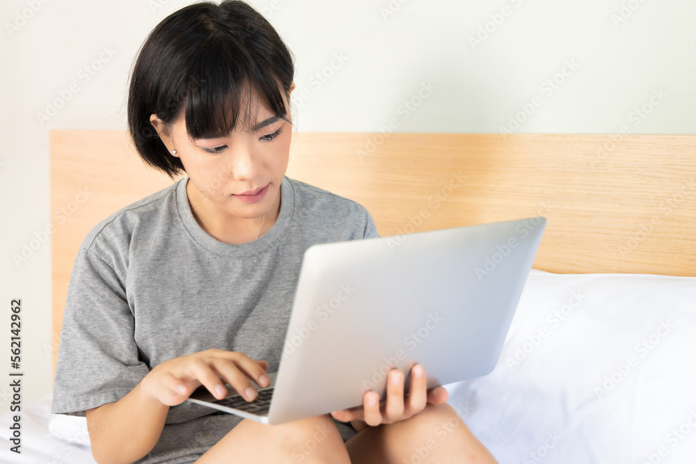 Serious asian woman starting working at home on her bed, concept of home office, working at home, work anywhere, telework, digital nomad Serious asian woman starting working at home on her bed, concept of home office, working at home, work anywhere, telework, digital nomad