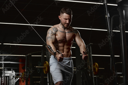 Daily workout session. Muscular man training shirtless in gym indoors. Doing lat pull down exercises. Relief body shape. Concept of sport, workout, strength