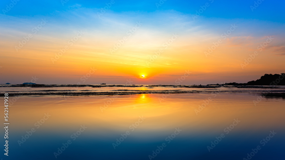 Beautiful sunset on the beach with reflection in water and sky.