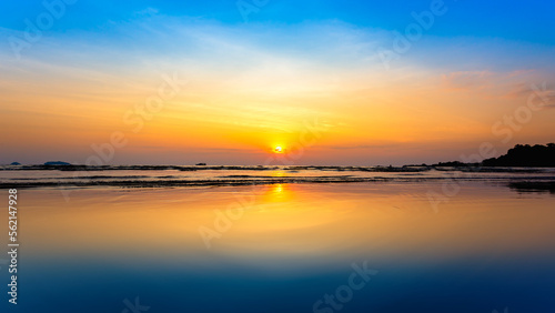 Beautiful sunset on the beach with reflection in water and sky.