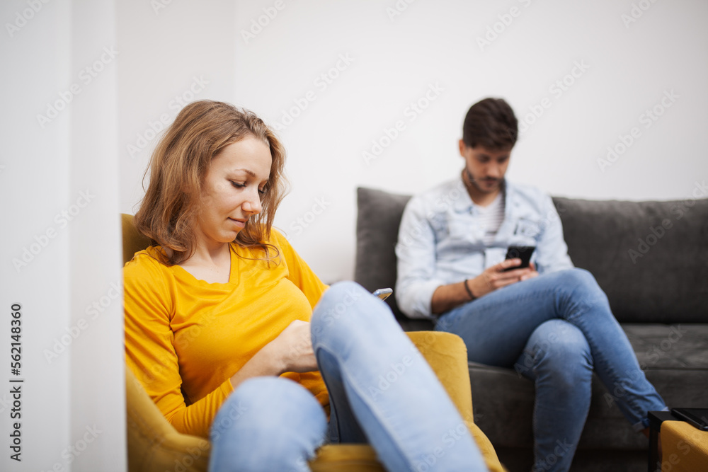 couple sitting at home livingroom looking at their smart phones