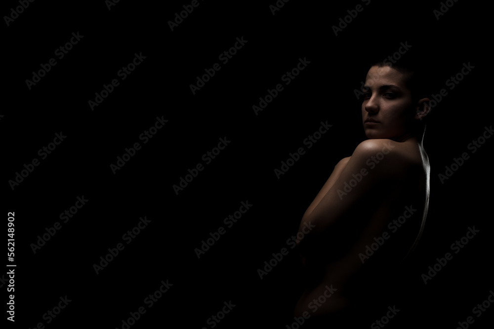 Fototapeta premium Portrait of a girl with short hair against dark background. Side lit contour slhouette...