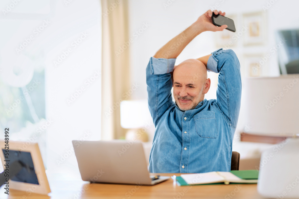 Middle aged businessman sitting at home and using laptop for work Middle aged businessman sitting at home and using laptop for work