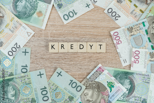 Word kredyt in Polish language, means loan or mortgage. Buying a house or apartment in Poland. Flat lay composition with złoty money, PLN zloty banknotes. 