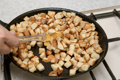 female hand stirs crackers fried in a frying pan