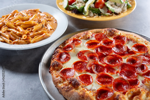 A view of a pepperoni pizza, penne Arrabbiata, and a California salad.