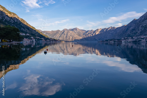 Panoramic view of bay of Kotor at sunrise in summer, Adriatic Mediterranean Sea, Montenegro, Balkans, Europe. Fjord winding along coastal towns. First sunbeams on Lovcen mountains. Water reflection