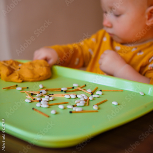 Toddler plays with modeling dough with small objects.