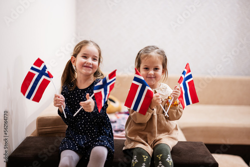 Canvas Print Two sisters are sitting on a couch at home with norwegian flags on hands