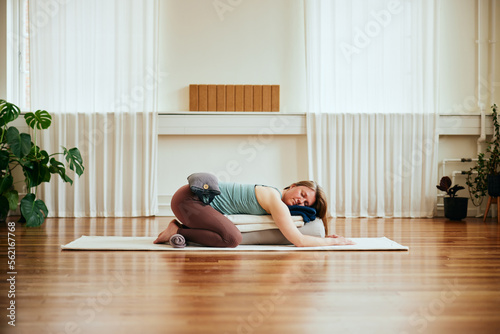 Woman doing restorative yoga using bolsters photo