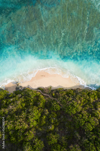 View from above, stunning aerial view of a person wlking on a beautiful beach bathed by a turquoise rough sea at sunset, Green Bowl Beach, South Bali, Indonesia.. © Travel Wild