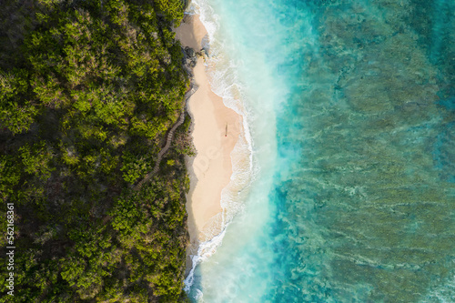 Obraz na płótnie View from above, stunning aerial view of a person wlking on a beautiful beach bathed by a turquoise rough sea at sunset, Green Bowl Beach, South Bali, Indonesia.. w salonie