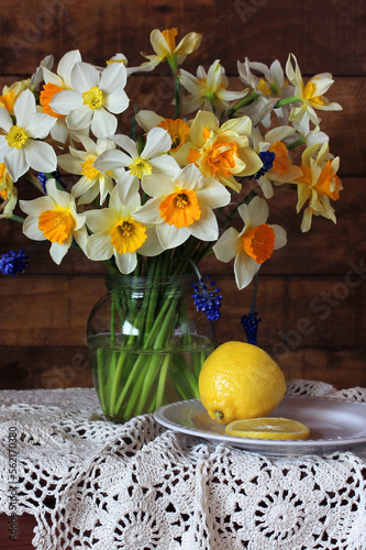 still life with yellow daffodils and lemon on a table.
