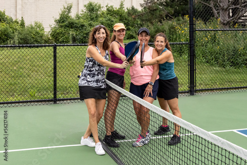 Four Female Pickleball Players Touch Paddles