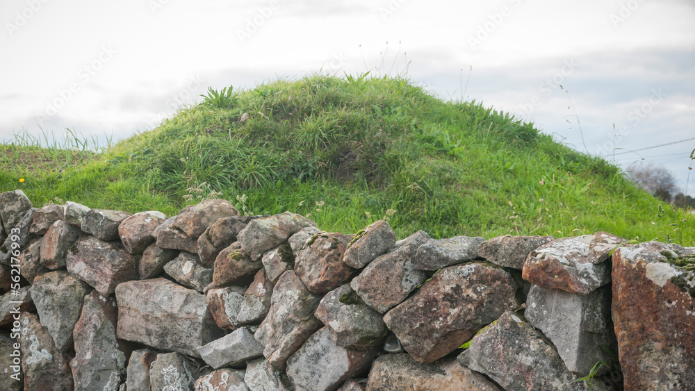 Muro rústico de piedras delante de colina redondeada