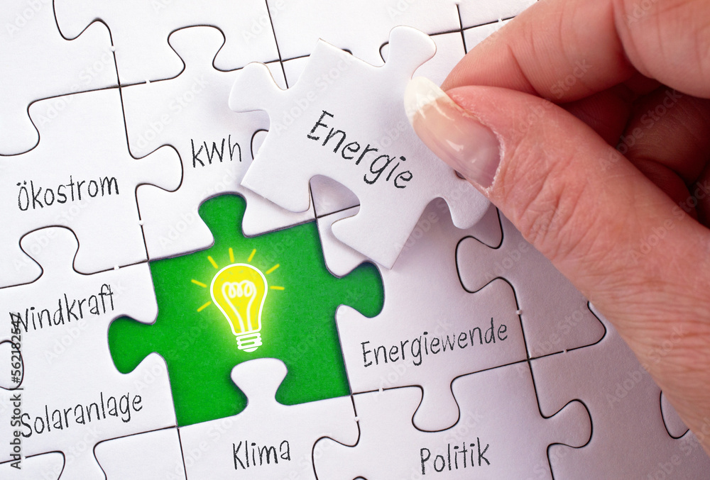 Energiewende und Ökostrom Puzzle mit Hand und Glühbirne Energiewende und Ökostrom Puzzle mit Hand und Glühbirne
