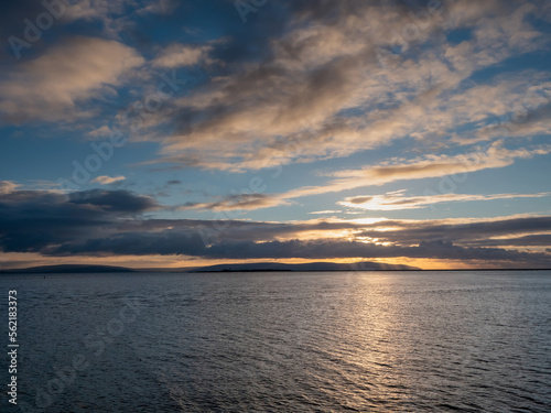 Stunning nature scene with sunset sky over ocean. Galway bay and Burren mountains in the background. Nobody. Irish landscape.